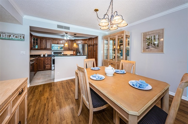 dining space with a textured ceiling, ceiling fan with notable chandelier, dark hardwood / wood-style floors, and ornamental molding