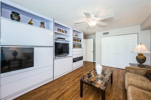 living room featuring dark hardwood / wood-style floors, ceiling fan, and a textured ceiling