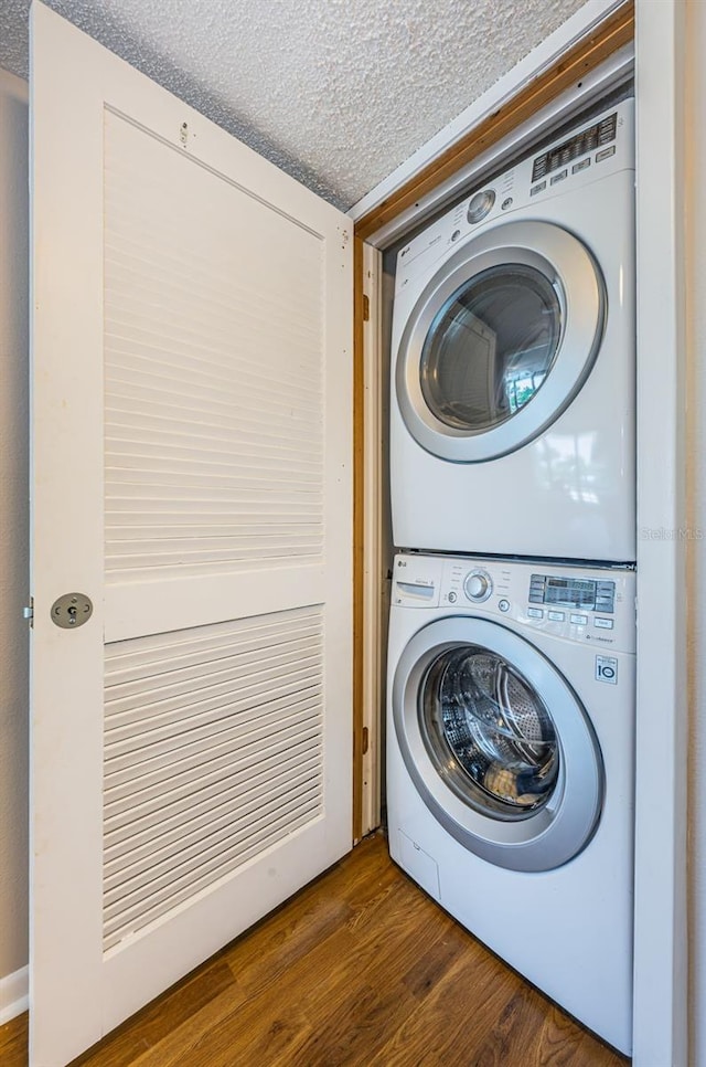 laundry area featuring dark hardwood / wood-style flooring, a textured ceiling, and stacked washer and dryer