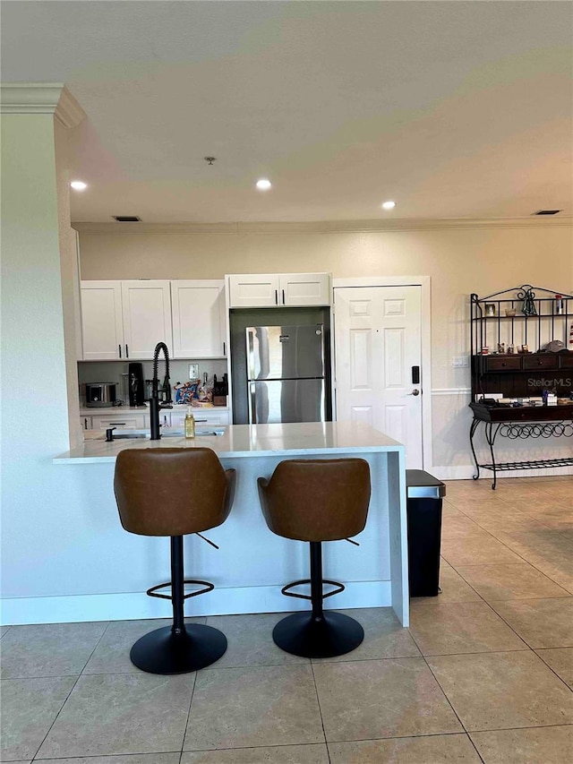 kitchen with light tile patterned floors, white cabinetry, and stainless steel fridge