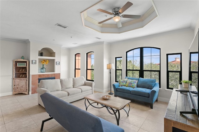 living room with a tray ceiling, light tile patterned floors, crown molding, and ceiling fan