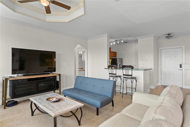 living room with light tile patterned flooring, crown molding, and ceiling fan