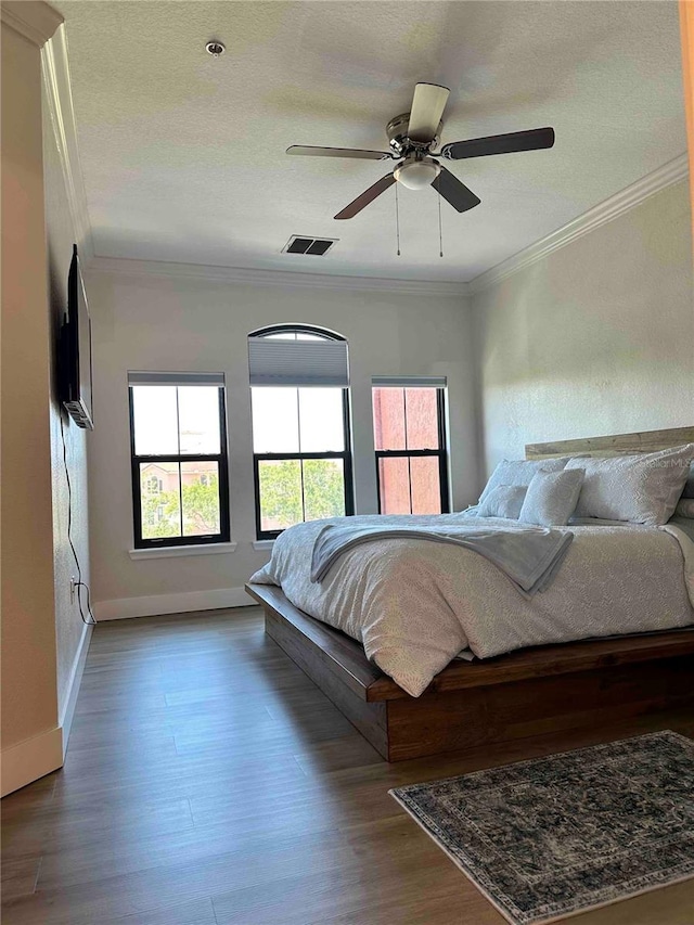 bedroom with a textured ceiling, crown molding, hardwood / wood-style floors, and ceiling fan