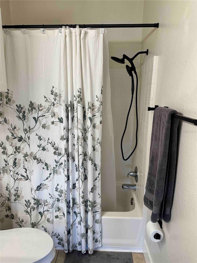 bathroom featuring toilet, shower / bath combo with shower curtain, and tile patterned flooring