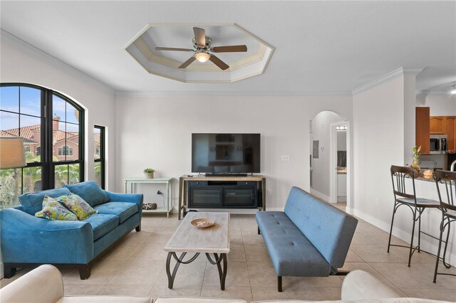 tiled living room featuring crown molding, ceiling fan, and a raised ceiling