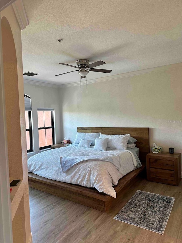 bedroom featuring ceiling fan, light hardwood / wood-style flooring, and a textured ceiling