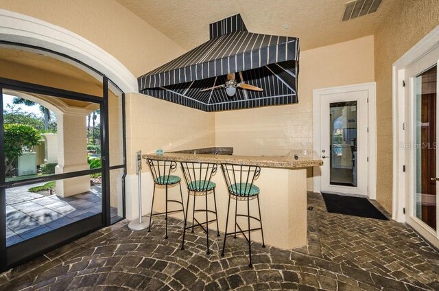 interior space with ceiling fan, a breakfast bar, a textured ceiling, and kitchen peninsula