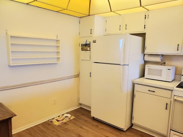 kitchen with white cabinets, white appliances, a drop ceiling, and dark wood-type flooring