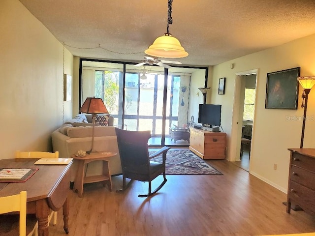 living room with ceiling fan, expansive windows, a textured ceiling, and hardwood / wood-style flooring