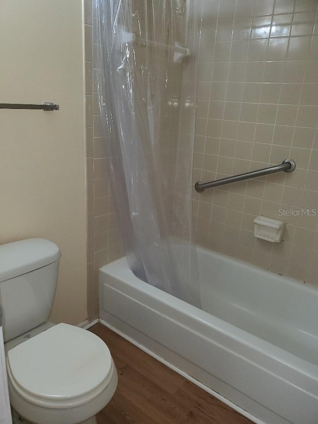 bathroom with hardwood / wood-style floors, shower / tub combo, and toilet