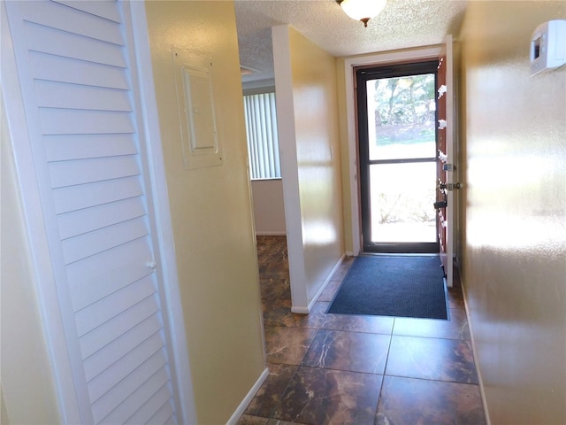 doorway to outside featuring a textured ceiling and dark tile patterned flooring