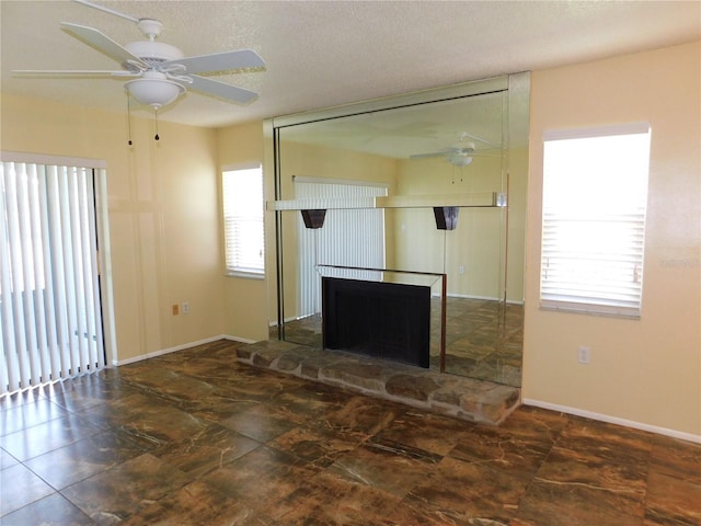 unfurnished living room featuring ceiling fan, a fireplace, and a textured ceiling