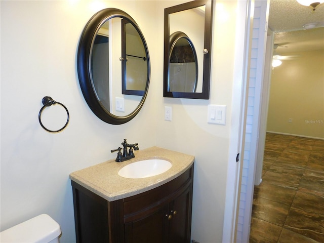 bathroom featuring ceiling fan, toilet, a textured ceiling, and vanity