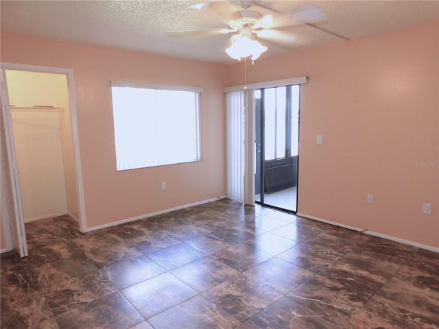 unfurnished room with ceiling fan and a textured ceiling