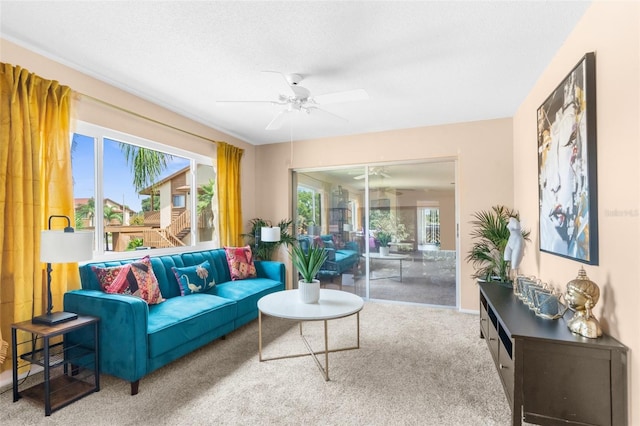 living room featuring carpet flooring, ceiling fan, and a textured ceiling