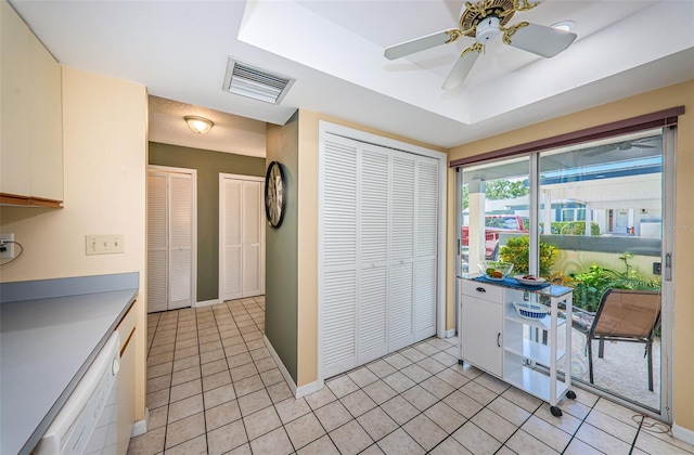 kitchen featuring white dishwasher, ceiling fan, light tile patterned flooring, and white cabinetry