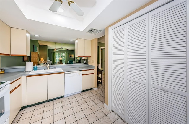 kitchen with sink, white dishwasher, a tray ceiling, light tile patterned flooring, and range