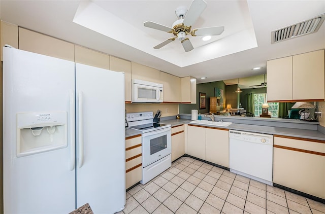 kitchen with white appliances, sink, ceiling fan, light tile patterned floors, and a tray ceiling