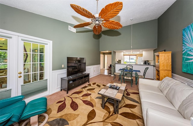 living room featuring a textured ceiling, ceiling fan, and light carpet