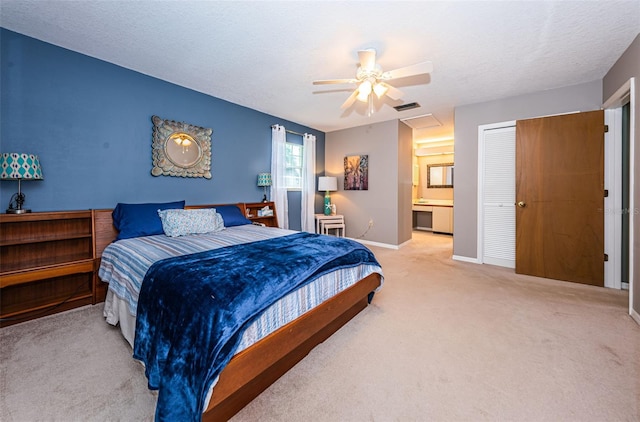 bedroom with ensuite bathroom, a textured ceiling, light colored carpet, ceiling fan, and a closet