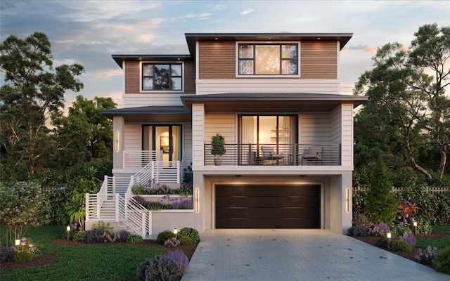 modern home with an attached garage, covered porch, stairs, decorative driveway, and stucco siding