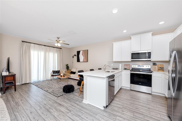 kitchen featuring kitchen peninsula, appliances with stainless steel finishes, light hardwood / wood-style floors, and white cabinetry