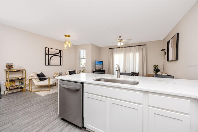 kitchen with white cabinets, ceiling fan with notable chandelier, sink, stainless steel dishwasher, and light hardwood / wood-style floors