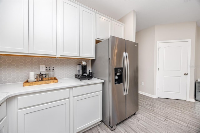 kitchen featuring white cabinetry, tasteful backsplash, stainless steel fridge, and light hardwood / wood-style flooring