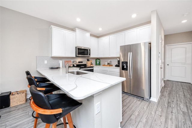 kitchen with kitchen peninsula, stainless steel appliances, white cabinetry, and sink