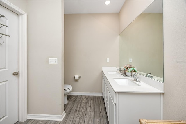 bathroom with hardwood / wood-style flooring, vanity, and toilet