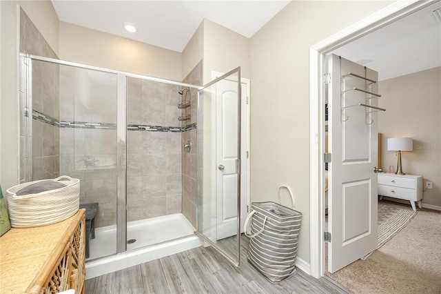 bathroom with a shower with shower door and hardwood / wood-style flooring