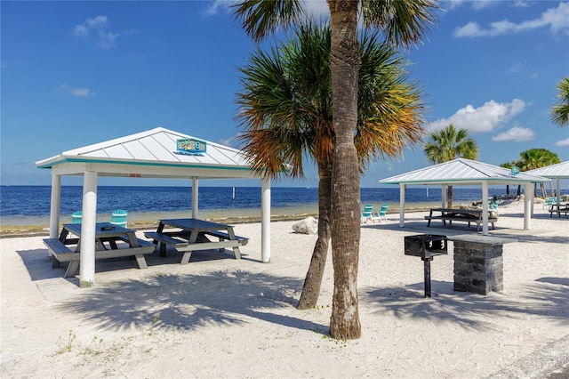 view of property's community with a gazebo, a water view, and a beach view