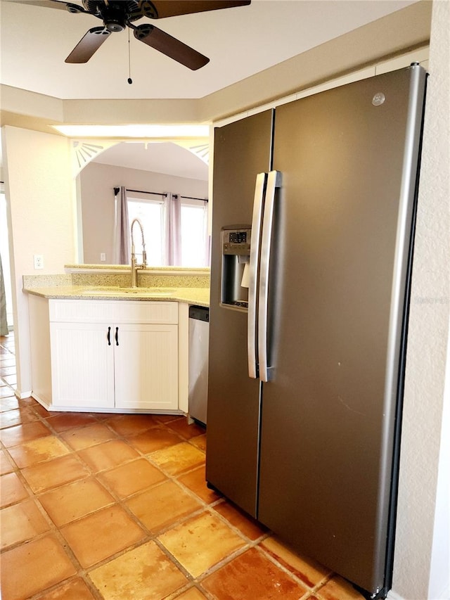 kitchen with appliances with stainless steel finishes, ceiling fan, sink, white cabinets, and light tile patterned flooring