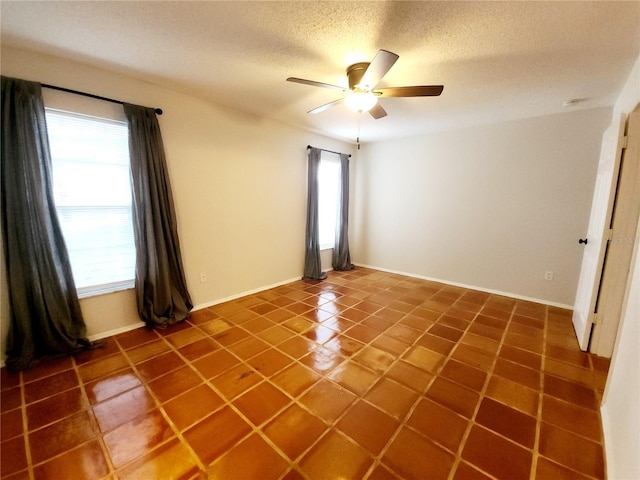 empty room with tile patterned flooring, a textured ceiling, and ceiling fan