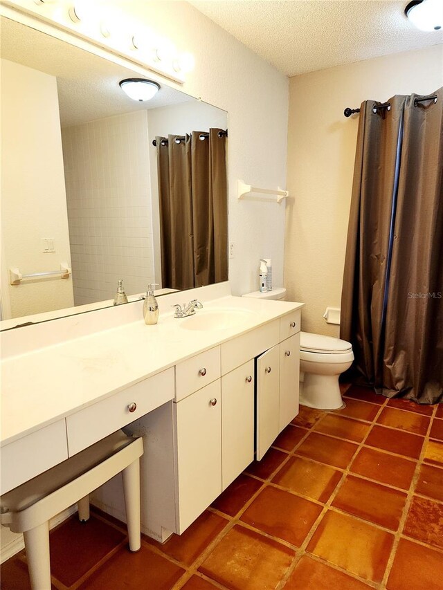 bathroom featuring vanity, tile patterned floors, a textured ceiling, and toilet