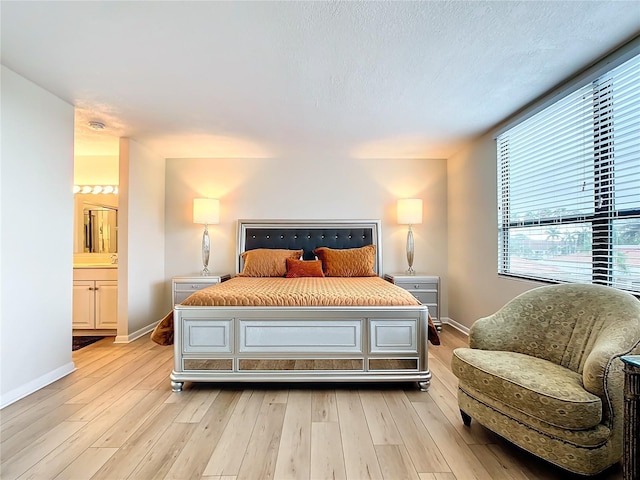 bedroom featuring ensuite bath, a textured ceiling, and light wood-type flooring