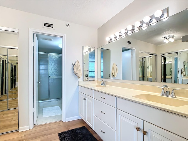 bathroom with hardwood / wood-style flooring, vanity, an enclosed shower, and a textured ceiling