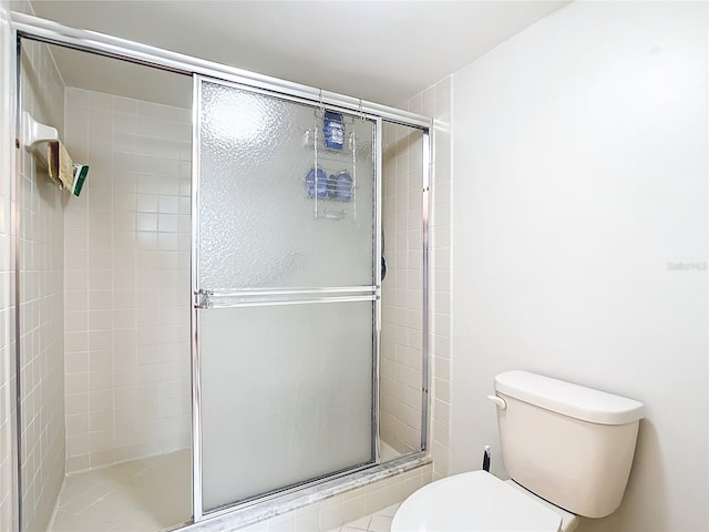 bathroom featuring toilet and a shower with shower door