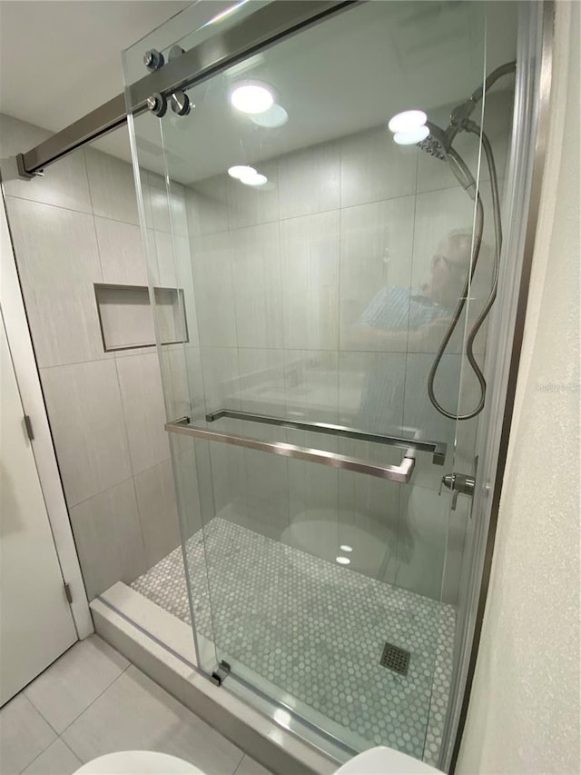 bathroom with toilet, an enclosed shower, and tile patterned flooring