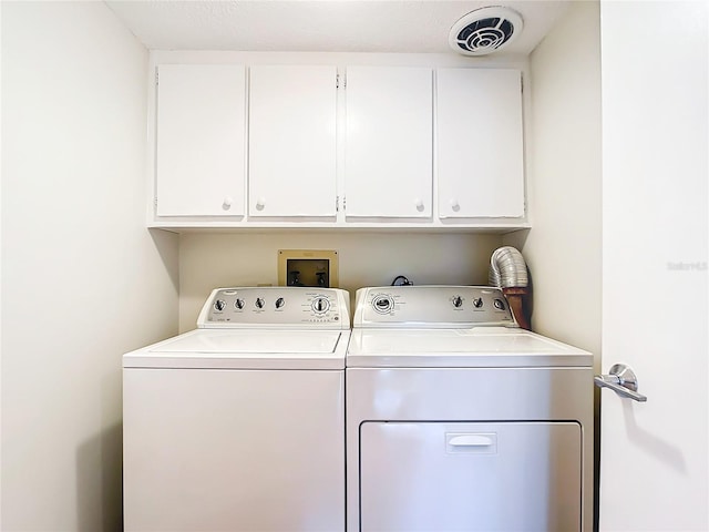 clothes washing area with washer and clothes dryer and cabinets