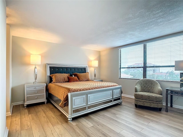 bedroom featuring a textured ceiling and light hardwood / wood-style flooring