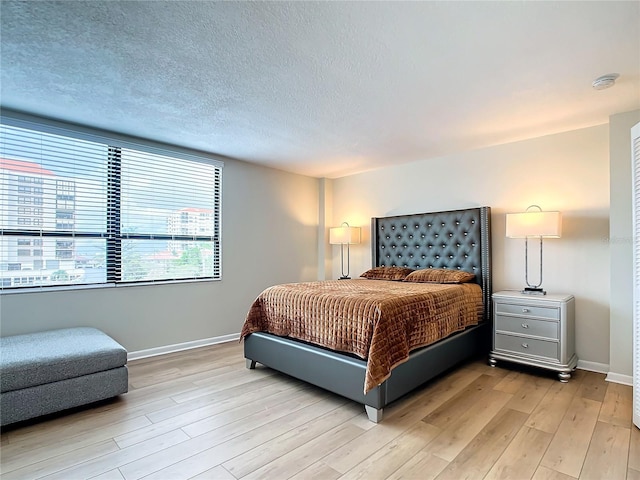 bedroom featuring a textured ceiling and light hardwood / wood-style flooring