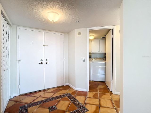 tiled foyer featuring washer and clothes dryer and a textured ceiling