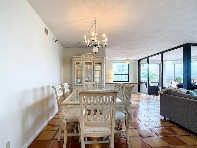 dining space featuring expansive windows, ceiling fan with notable chandelier, dark tile patterned flooring, and a textured ceiling