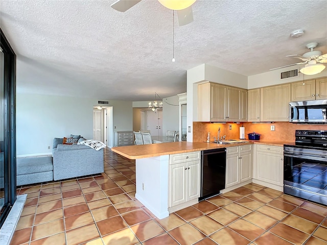 kitchen with light tile patterned floors, appliances with stainless steel finishes, kitchen peninsula, ceiling fan with notable chandelier, and decorative backsplash