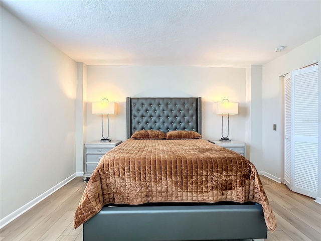 bedroom featuring a closet, a textured ceiling, and light wood-type flooring