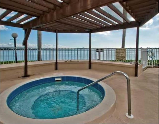 view of swimming pool featuring a hot tub and a water view