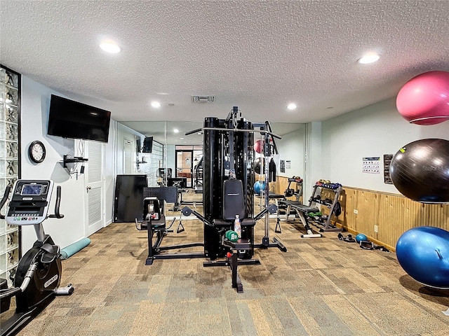 exercise room featuring light carpet and a textured ceiling