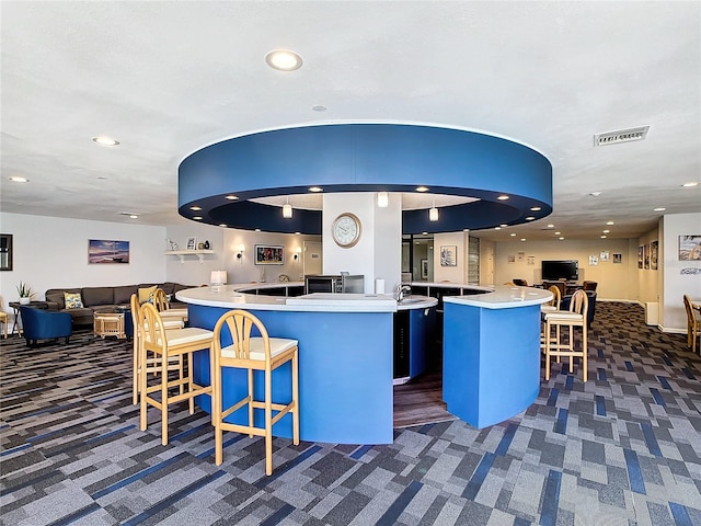 kitchen with a kitchen island, a breakfast bar area, dark carpet, and kitchen peninsula