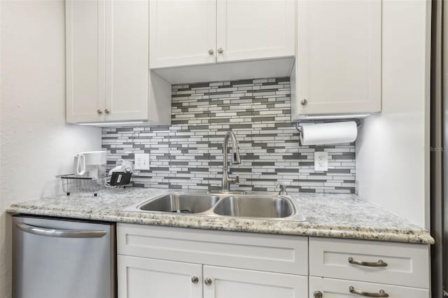 kitchen featuring decorative backsplash, light stone counters, stainless steel dishwasher, sink, and white cabinets